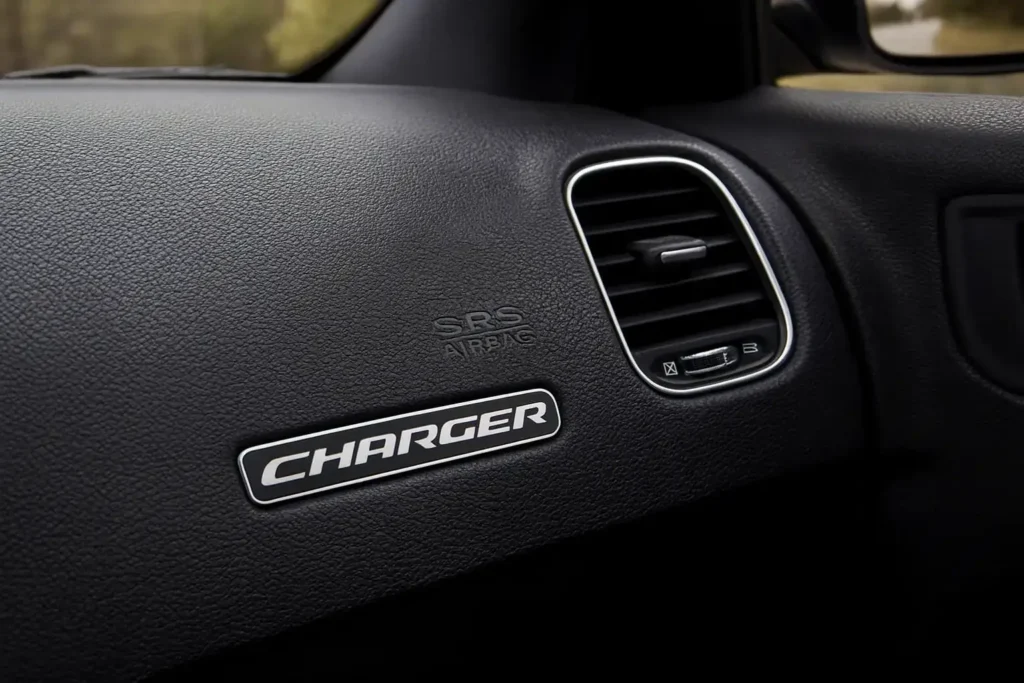 2016 Dodge Charger SRT black dashboard close up showing CHARGER badge and right air vent with SRS Airbag embossin 2016 Dodge Charger SRT black dashboard close up showing CHARGER badge and right air vent with SRS Airbag embossin