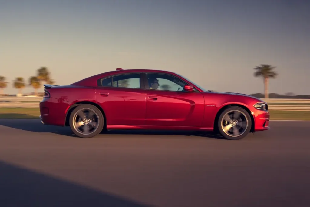 Side profile of 2016 Dodge Charger RT in motion on track highlighting muscular fenders alloy wheels and sleek performance sedan design Side profile of 2016 Dodge Charger RT in motion on track highlighting muscular fenders alloy wheels and sleek performance sedan design