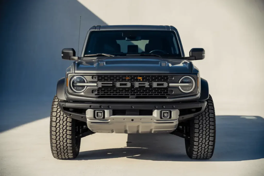 Direct front view of the grey 2025 Ford Bronco Raptor in soft daylight highlighting signature grille and aggressive skid plate Direct front view of the grey 2025 Ford Bronco Raptor in soft daylight highlighting signature grille and aggressive skid plate