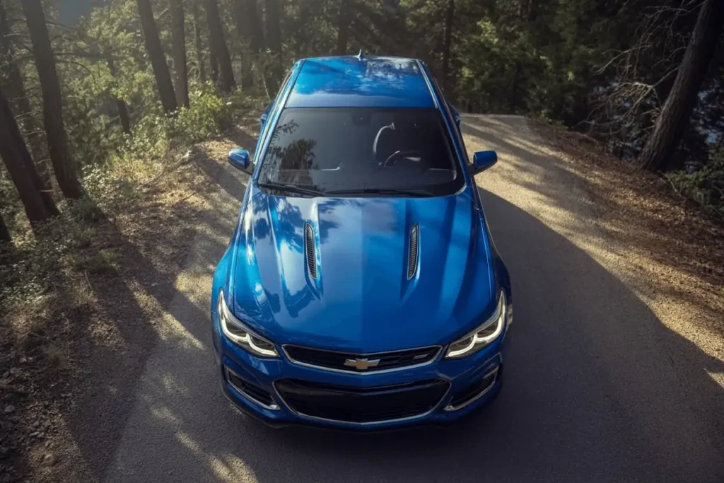 High angle view of blue 2016 Chevrolet SS hood twin vents and LED headlights glowing on shaded mountain asphalt High angle view of blue 2016 Chevrolet SS hood twin vents and LED headlights glowing on shaded mountain asphalt