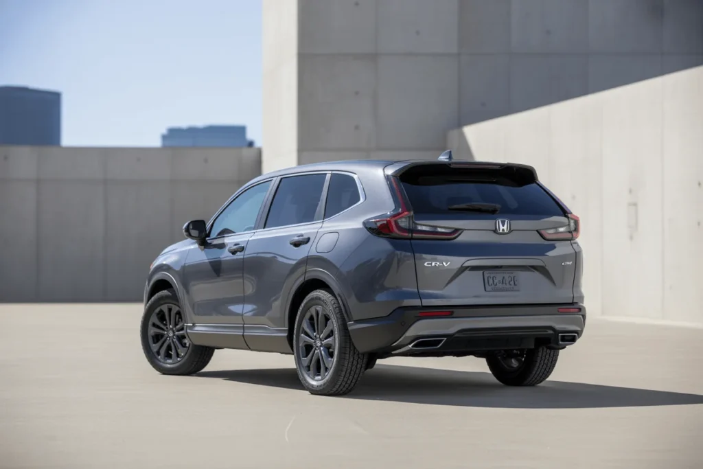 Rear three quarter view of 2025 Honda CR V in open rooftop setting showing L shaped LED taillights and dual exhaust Rear three quarter view of 2025 Honda CR V in open rooftop setting showing L shaped LED taillights and dual exhaust