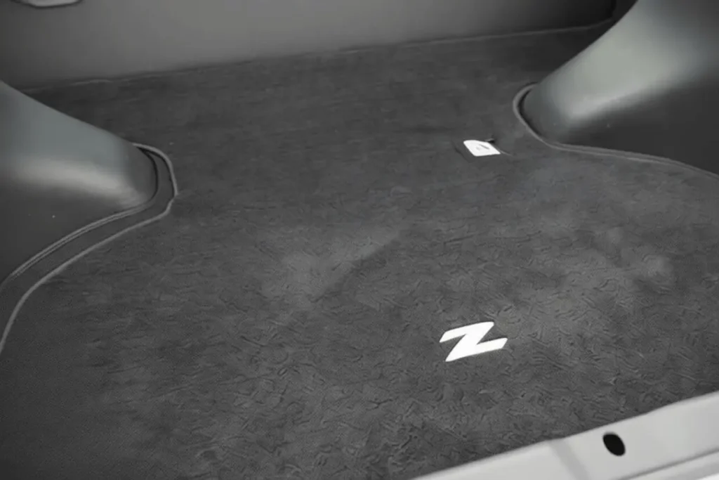 2014 Nissan 370Z Nismo cargo area closeup textured black trunk mat raised wheel arches white Z logo 2014 Nissan 370Z Nismo cargo area closeup textured black trunk mat raised wheel arches white Z logo