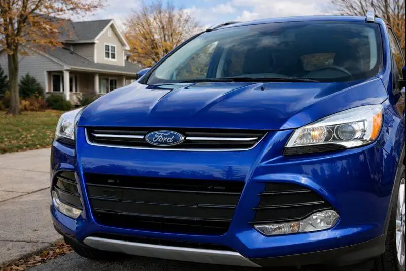 2016 Ford Escape Titanium front close up three quarter view showing Ford grille projector headlights Deep Impact Blue paint autumn suburb street 2016 Ford Escape Titanium front close up three quarter view showing Ford grille projector headlights Deep Impact Blue paint autumn suburb street