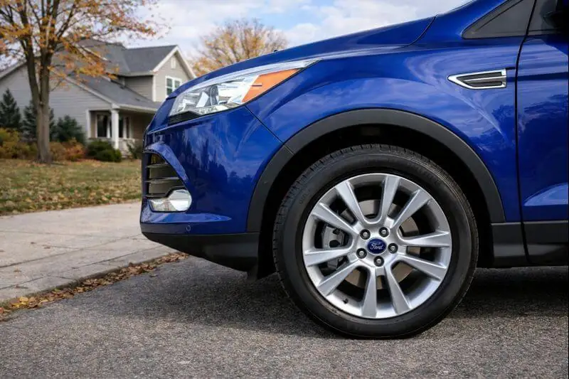 2016 Ford Escape Titanium front wheel close up silver multi spoke alloy rim black fender trim autumn suburb driveway 2016 Ford Escape Titanium front wheel close up silver multi spoke alloy rim black fender trim autumn suburb driveway