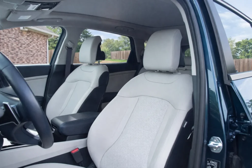 2023 Kia Sportage Plug in Hybrid front seat interior side view from open driver door with light perforated upholstery 2023 Kia Sportage Plug in Hybrid front seat interior side view from open driver door with light perforated upholstery