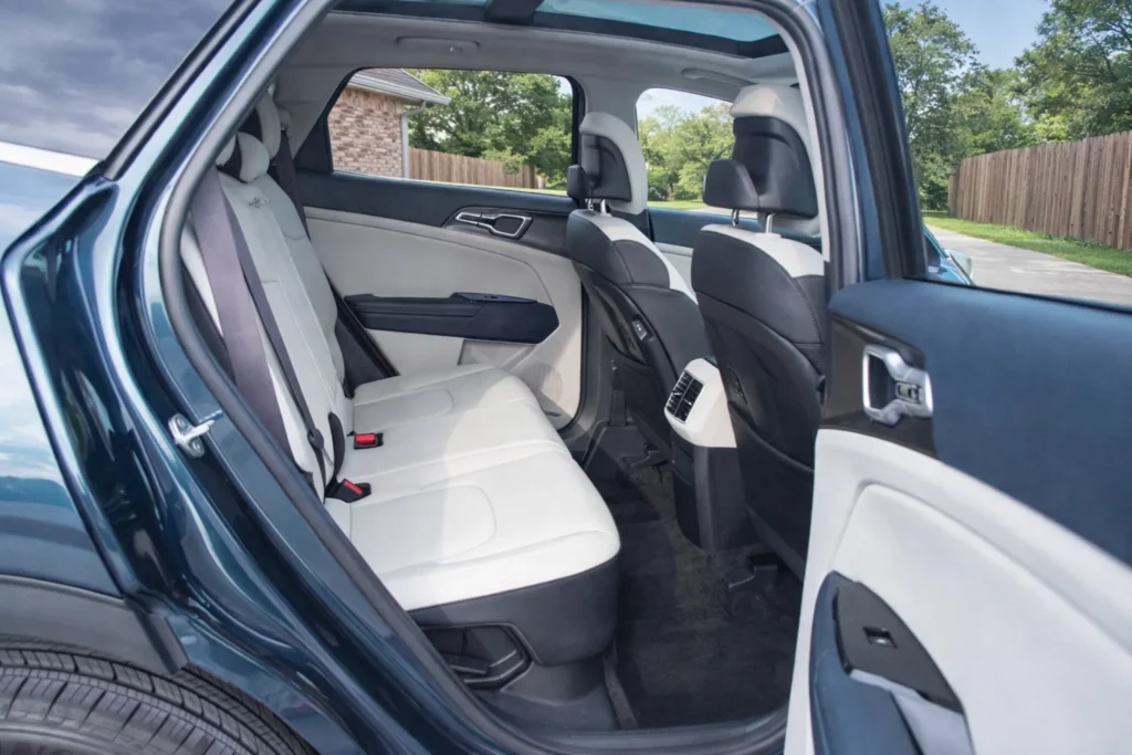 2023 Kia Sportage Plug in Hybrid rear seat view from open door on driveway with light upholstery and sunroof 2023 Kia Sportage Plug in Hybrid rear seat view from open door on driveway with light upholstery and sunroof