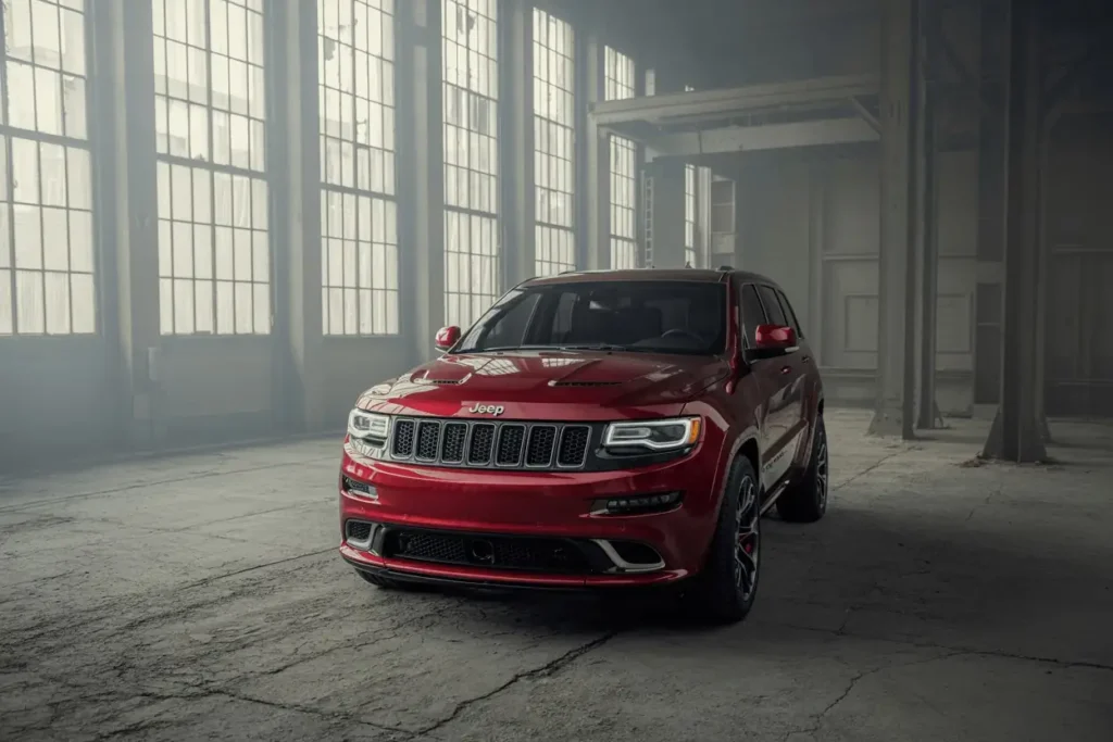 Aggressive front angle of 2016 Jeep Grand Cherokee SRT in red LED headlights glowing inside abandoned factory space Aggressive front angle of 2016 Jeep Grand Cherokee SRT in red LED headlights glowing inside abandoned factory space
