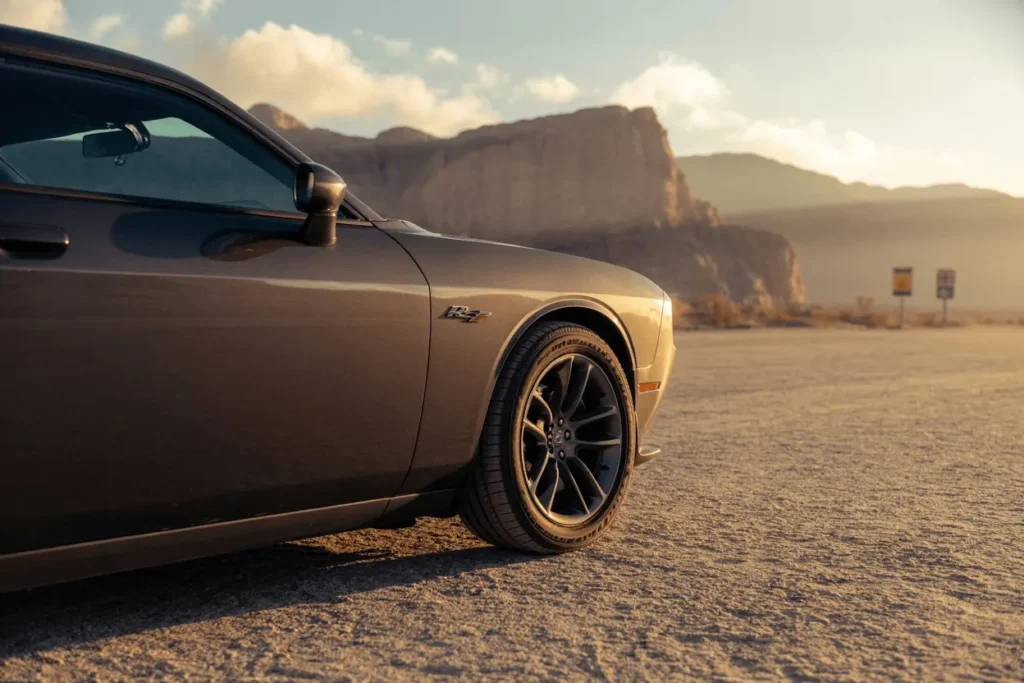 Detail shot of 2013 Dodge Challenger RT Plus front fender RT badge and alloy wheel in evening desert Detail shot of 2013 Dodge Challenger RT Plus front fender RT badge and alloy wheel in evening desert
