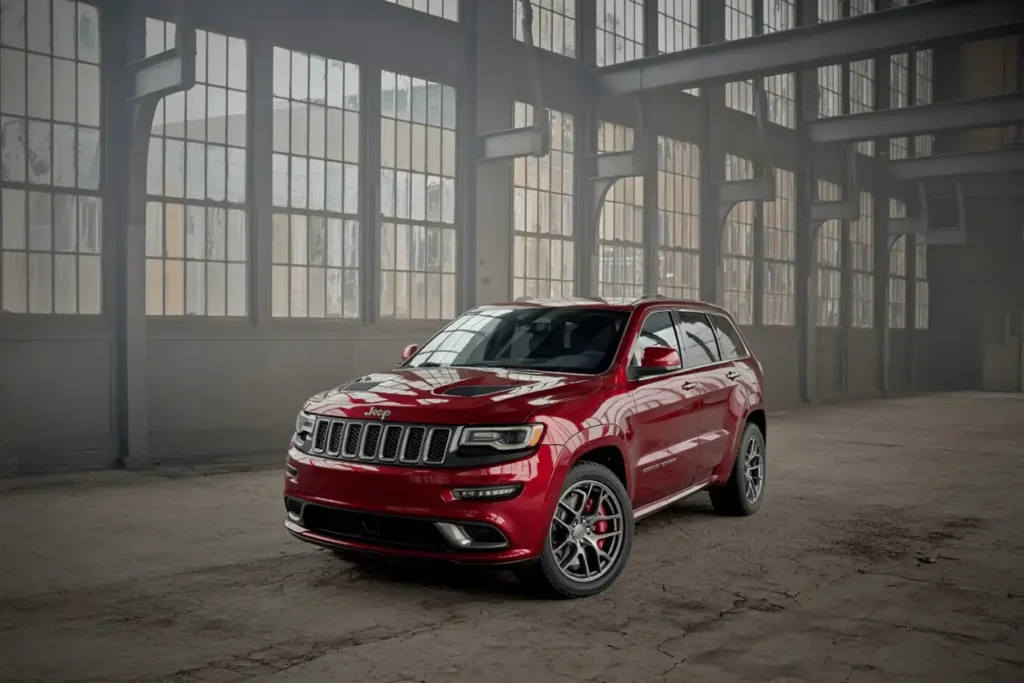 Front three quarter view of 2016 Jeep Grand Cherokee SRT red SUV with alloy wheels parked in moody warehouse Front three quarter view of 2016 Jeep Grand Cherokee SRT red SUV with alloy wheels parked in moody warehouse