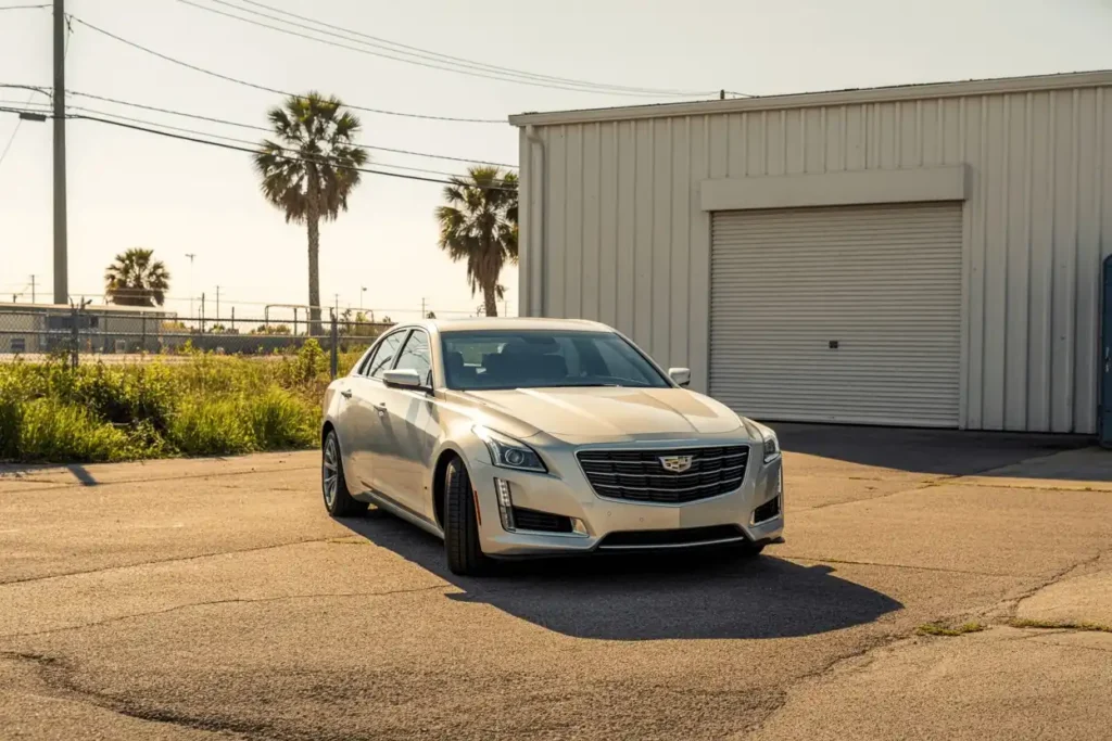 Front three quarter view of a champagne 2016 Cadillac CTS sedan in an industrial lot palm trees and warehouse backdrop Front three quarter view of a champagne 2016 Cadillac CTS sedan in an industrial lot palm trees and warehouse backdrop