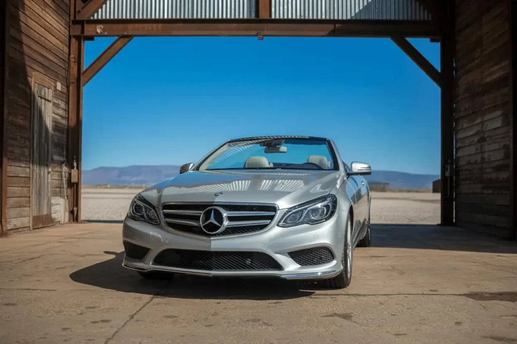Front view of 2014 Mercedes Benz E350 Cabriolet under wooden barn silver paint LED headlights and wide grille Front view of 2014 Mercedes Benz E350 Cabriolet under wooden barn silver paint LED headlights and wide grille