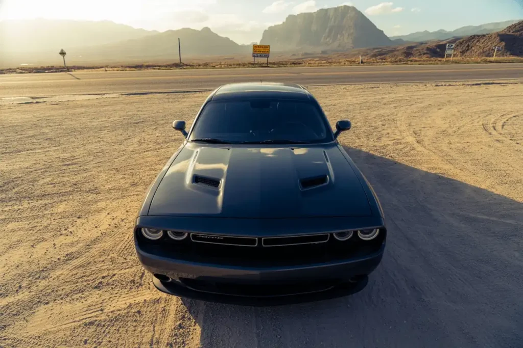 High front view of 2013 Dodge Challenger RT Plus highlighting vented hood wide body lines empty desert road High front view of 2013 Dodge Challenger RT Plus highlighting vented hood wide body lines empty desert road