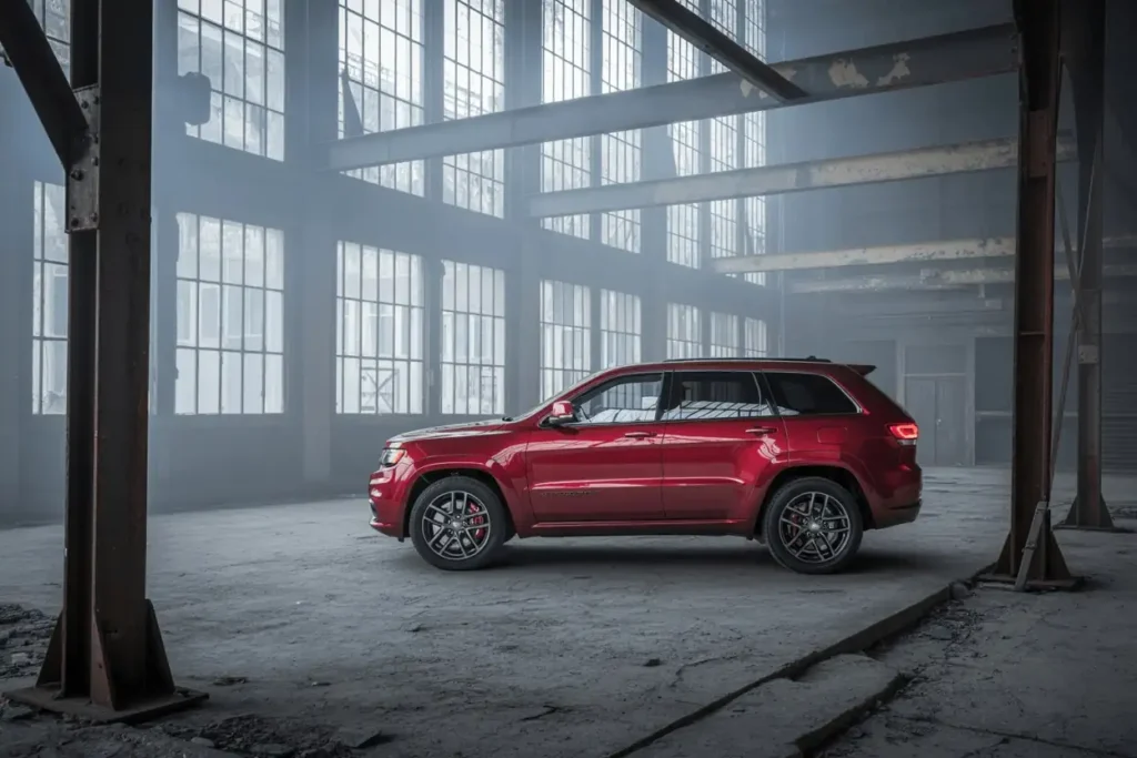 Side profile view of 2016 Jeep Grand Cherokee SRT in red lowered stance highlighted against tall industrial windows Side profile view of 2016 Jeep Grand Cherokee SRT in red lowered stance highlighted against tall industrial windows