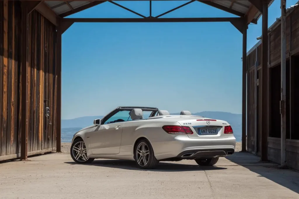 Straight rear view of 2014 Mercedes Benz E350 Cabriolet parked under wooden shed dual exhausts framed by desert mountains Straight rear view of 2014 Mercedes Benz E350 Cabriolet parked under wooden shed dual exhausts framed by desert mountains