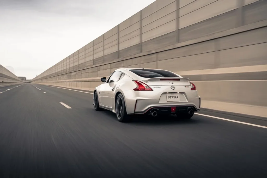 Straight rear view of 2014 Nissan 370Z Nismo cruising highway LED taillights glowing dual exhaust tips pearl white paint Straight rear view of 2014 Nissan 370Z Nismo cruising highway LED taillights glowing dual exhaust tips pearl white paint