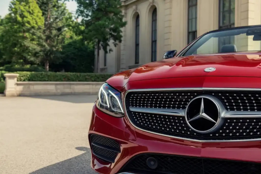 Tight front fascia shot of 2015 Mercedes Benz E400 Cabriolet diamond grille and big emblem sunlit courtyard greenery Tight front fascia shot of 2015 Mercedes Benz E400 Cabriolet diamond grille and big emblem sunlit courtyard greenery