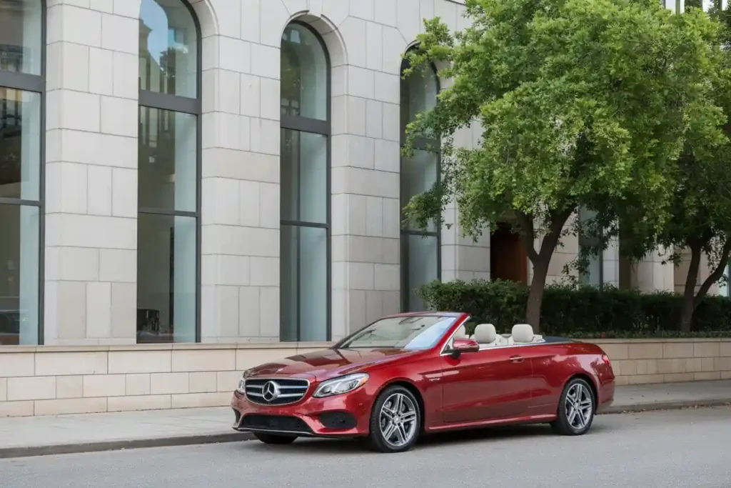 Wide side profile of 2015 Mercedes Benz E400 Cabriolet top down with light seats modern arched windows shade tree Wide side profile of 2015 Mercedes Benz E400 Cabriolet top down with light seats modern arched windows shade tree