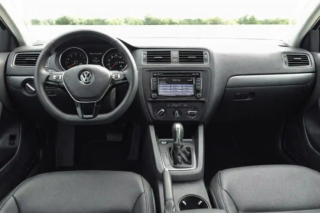 A side profile rolling shot of a gray 2015 Volkswagen Jetta 1.8T SE shows the full four door silhouette and both wheels with a motion blurred rock wall behind it A side profile rolling shot of a gray 2015 Volkswagen Jetta 1.8T SE shows the full four door silhouette and both wheels with a motion blurred rock wall behind it